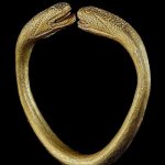 A MASSIVE INDIAN GOLD BANGLE WITH SNAKE HEADS