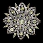 Circular brooch in the form of a stylized eight-petalled flower, of chrysoberyls and pink topazes set in silver