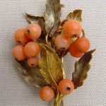 Brooch. A spray of leaves and fruit in coral and bloomed two-colour gold.