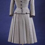 Blue and white checked wool suit comprising a fitted jacket with a notched hem, and a full and stiffened skirt. With blue silk grosgrain bows.